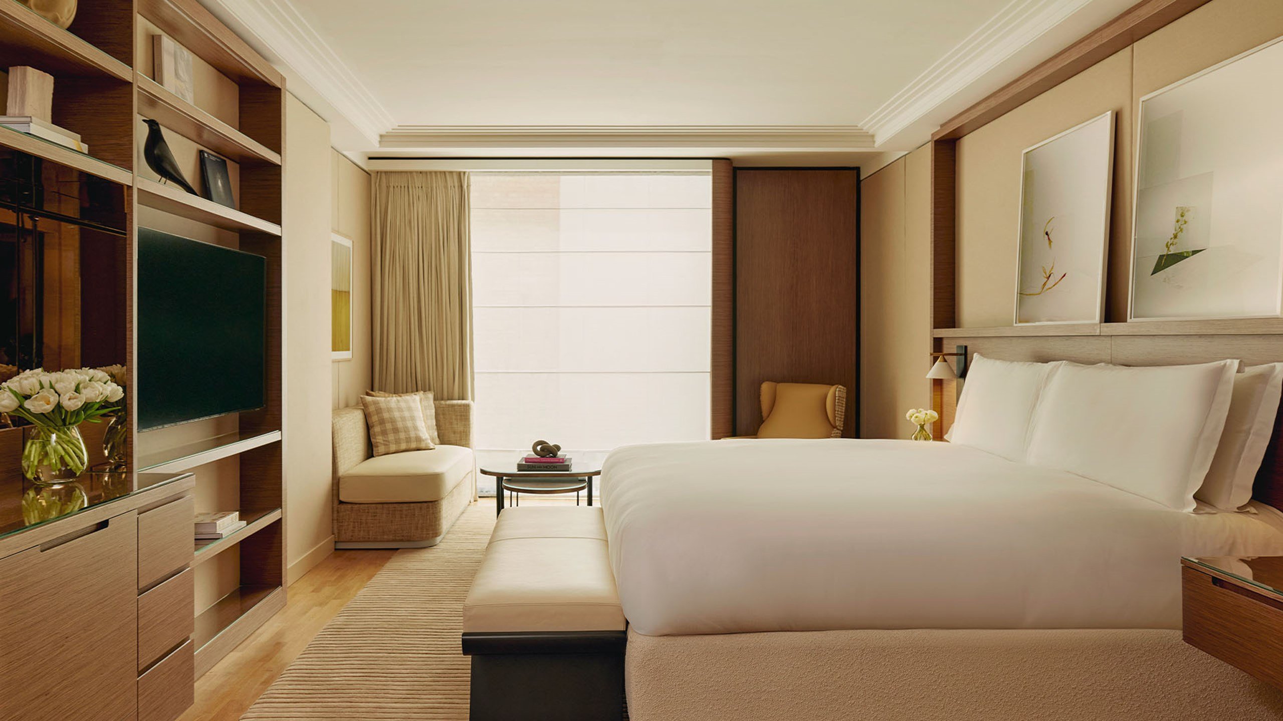 Another angle of the elegant bedroom, complete with a sitting area, soft lighting, and a refined, neutral color palette.