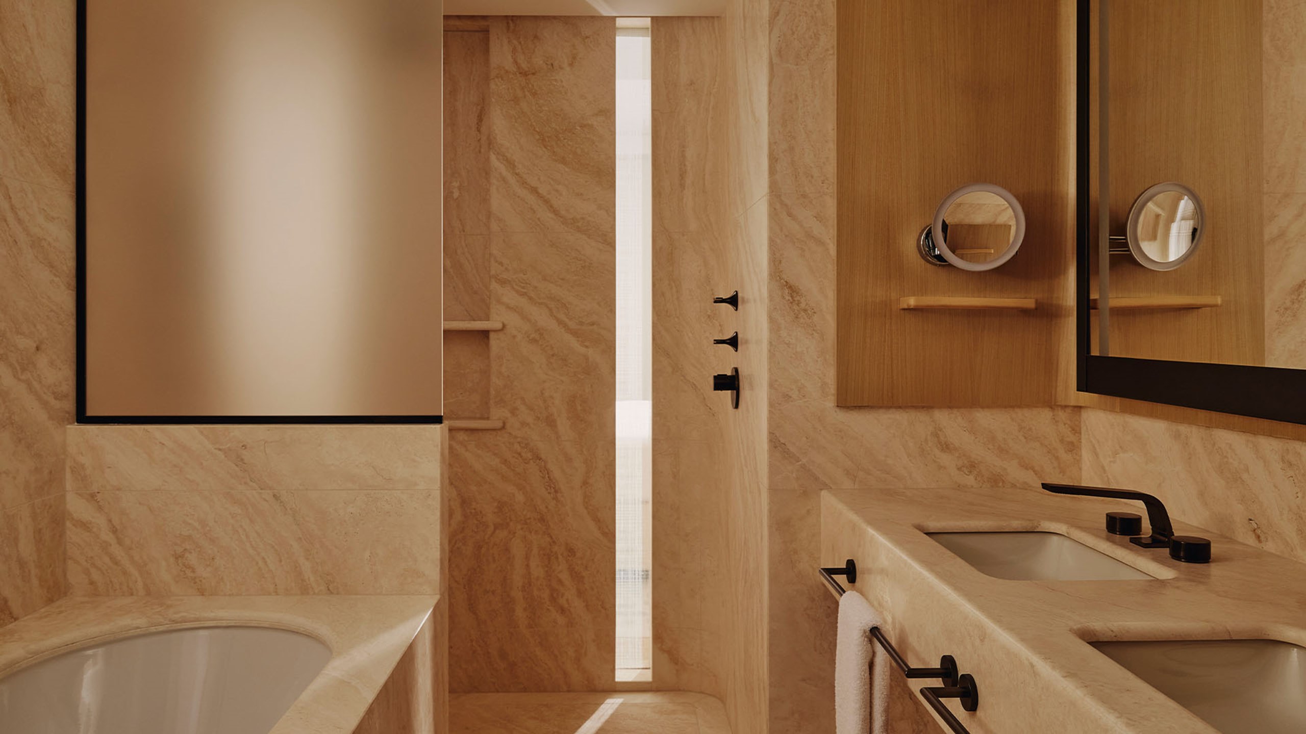 A dual-vanity bathroom with a soft beige marble finish, featuring sleek black fixtures and a relaxing ambiance.
