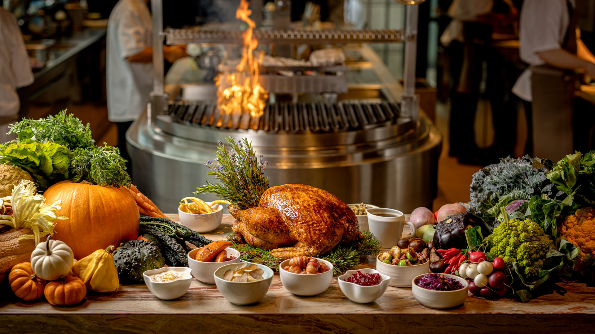 A Christmas table set with a roasted turkey, sides, flowers, candles and gold decorations.