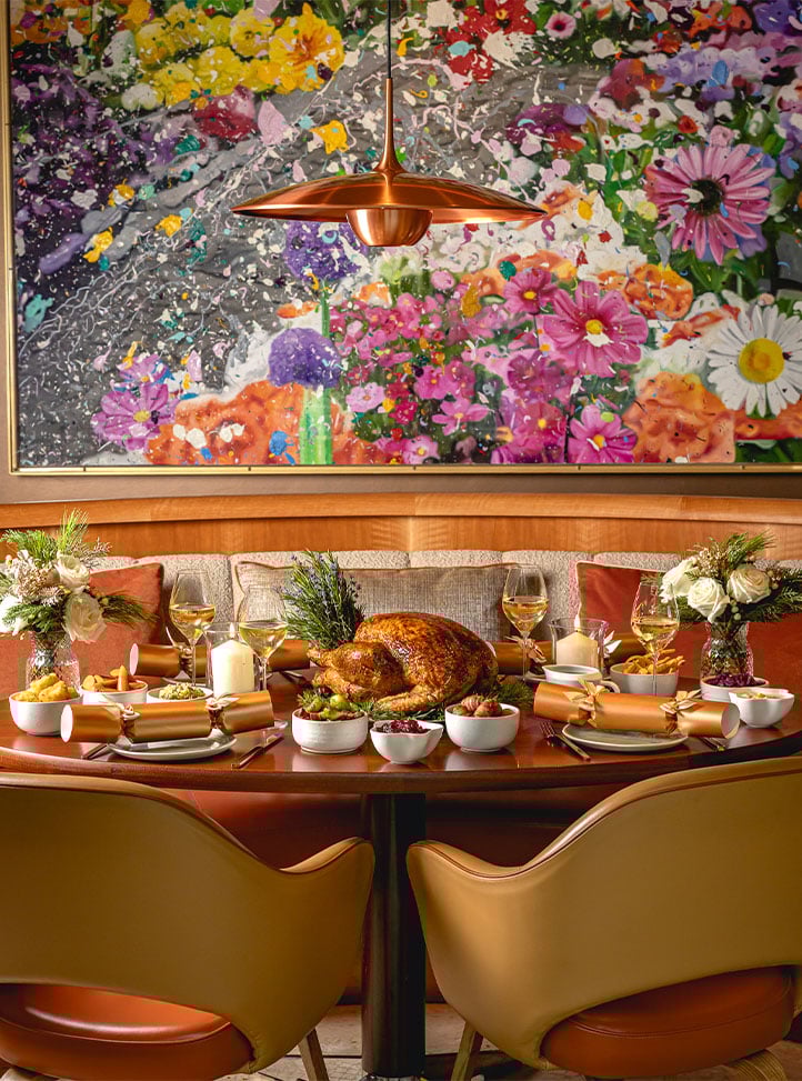 A holiday feast with a roast turkey, wine glasses and crackers on a warmly decorated table.