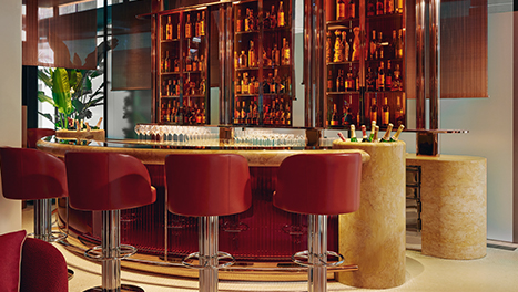Four red bar stools against a gold and luxe bar at The Emory Bar