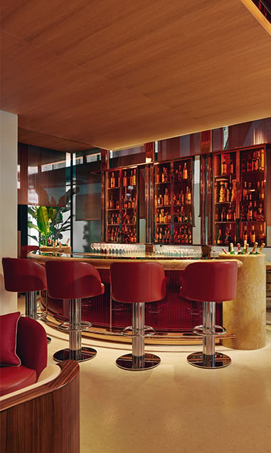 Four red bar stools against a gold and luxe bar at The Emory Bar