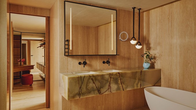 Balcony Park Suite bathroom. A bath sits to the right. A marble sink sits in the foreground. A mirror sits above the sink.