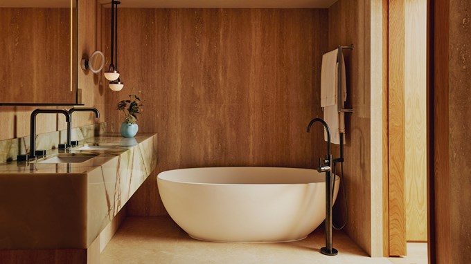 Standalone marble bathtub in bathroom with wooden panel decor and modern black furnishings.