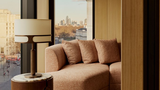 The Emory Corner Park Suite sitting area - A window sits to the left. A couch with three cushions sits in front of it. A lamp sits to the left.