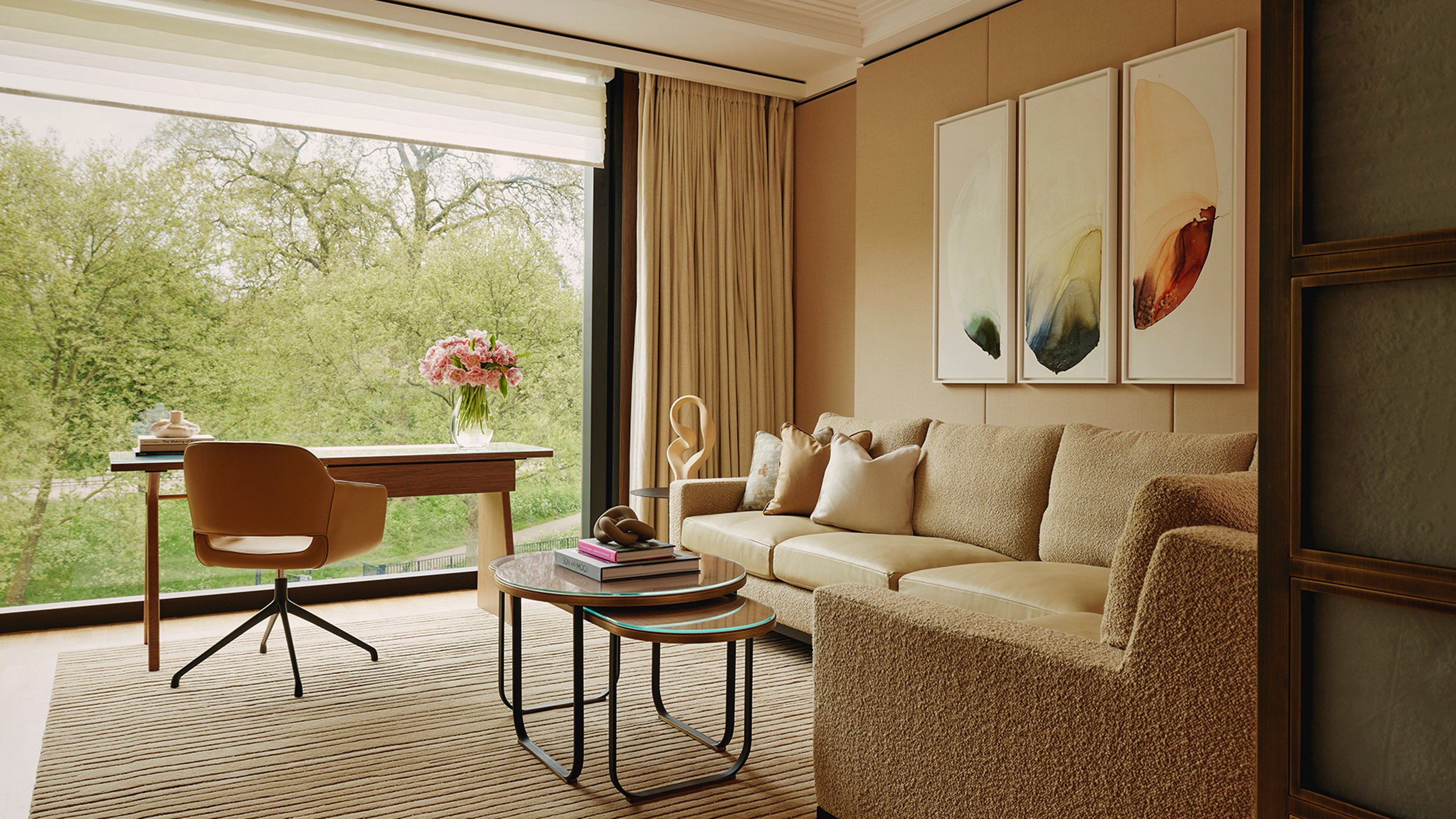 Corner sofa in a cream material next to a desk and curved office chair looking out towards a park view