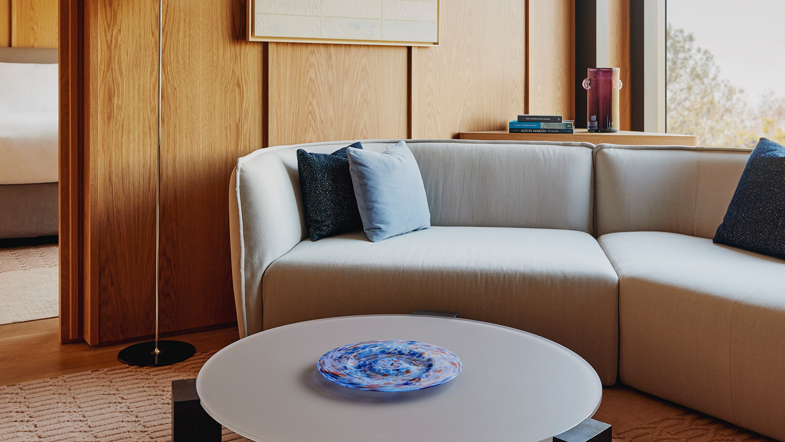 The edge of a grey sofa with a variety of blue cushions placed on top, with wooden panelling behind