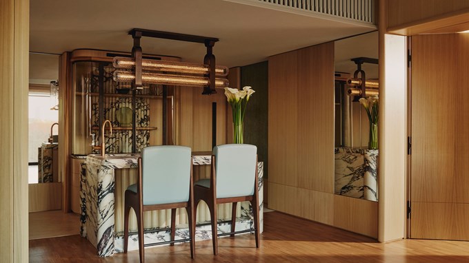 High bar stools with wooden legs and blue padding, sat in front of grand marble bar in the Emory Park Suite