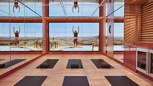 Yoga room at Surrenne. Black yoga mats are on the floor and a screen projection with a yoga instructor is on the wall